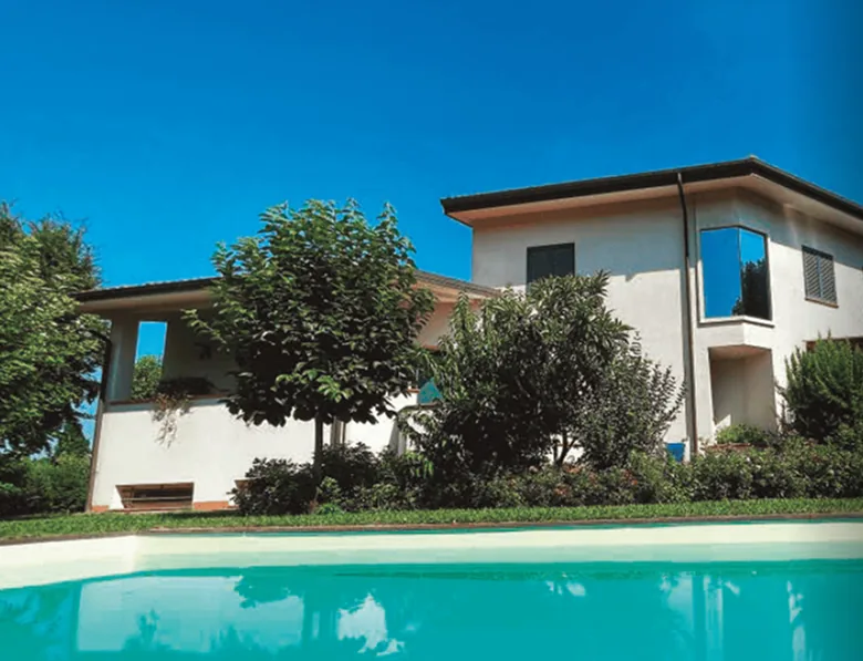 A white two-storey villa behind a swimming pool