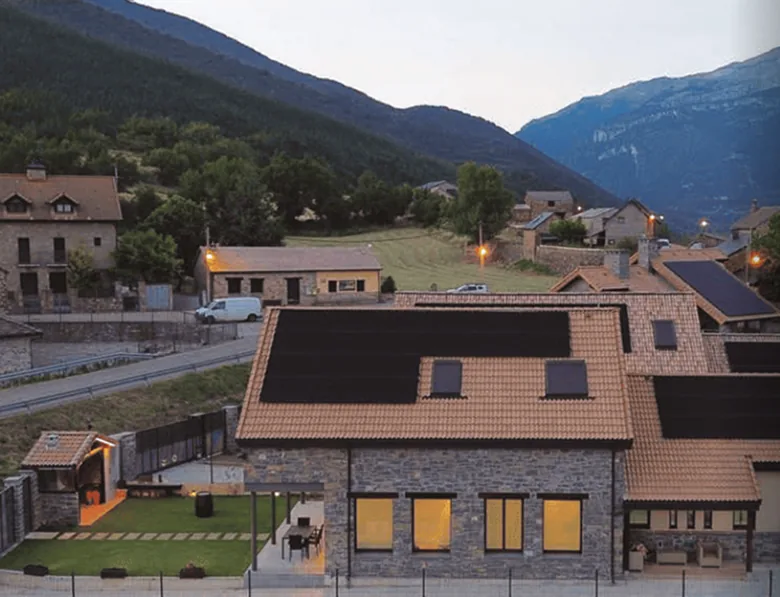 A stone house with solar panels on the roof in a mountain village
